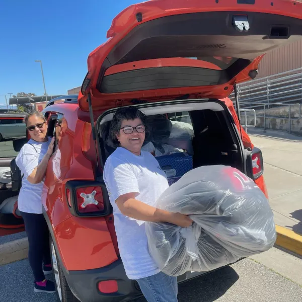 Chairwoman Juana Sotelo holding bag of warm clothes and Sister Cythia Perez
